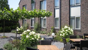 A brick building with large windows and a garden patio with outdoor seating. - Hotel Ekamper (Roodeschool)