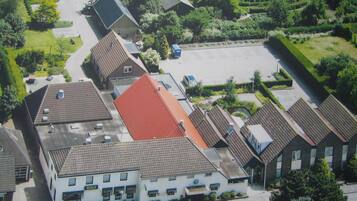 Eine Vogelperspektive eines Wohngebiets mit einem Gebäude mit der Aufschrift "BOLS", das ein rotes Dach, zahlreiche Fenster und einen Parkplatz hat.