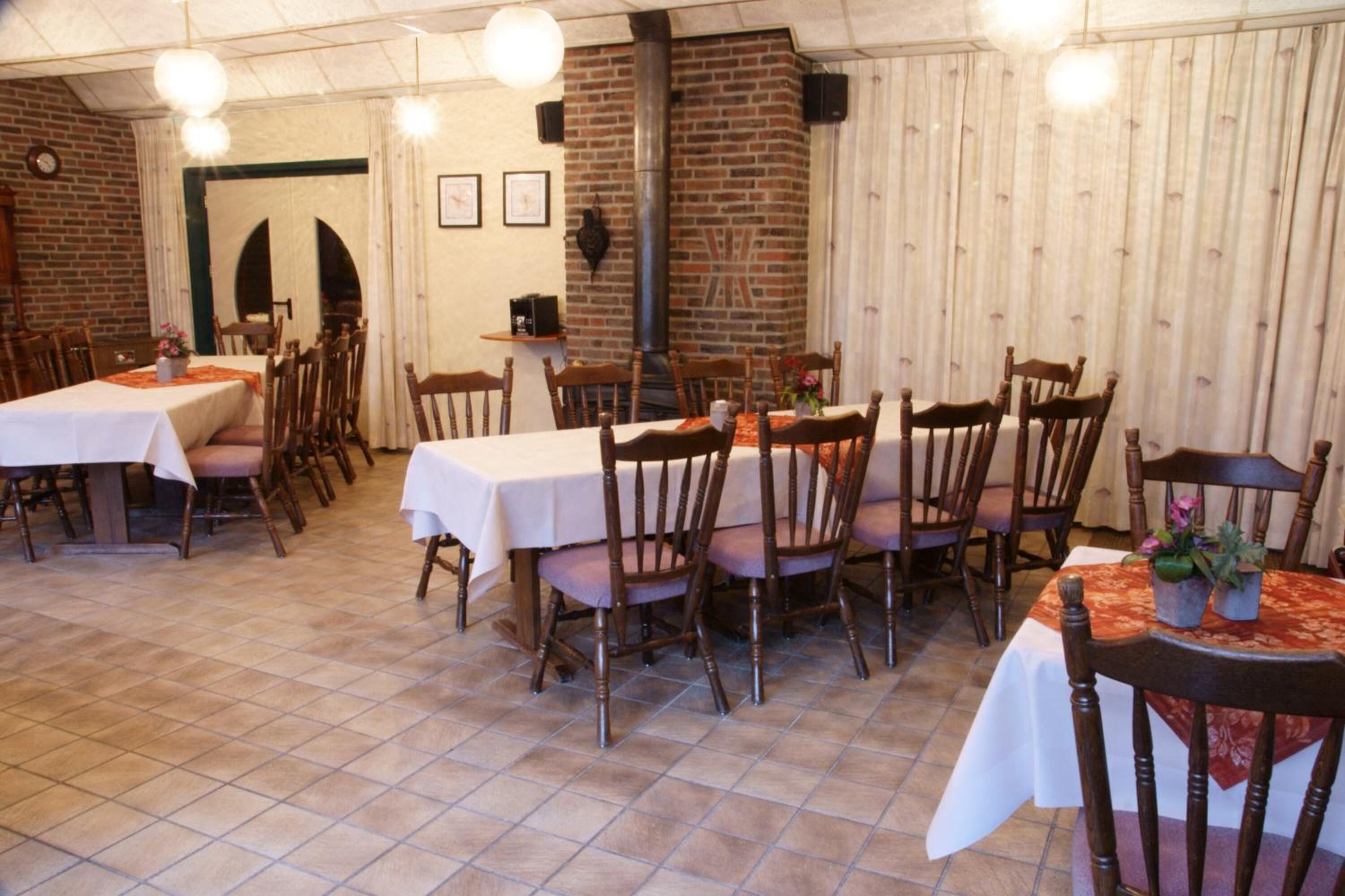 Ein Restaurant mit mehreren Tischen und Stühlen, Backsteinwänden und einem gefliesten Boden.