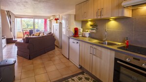 Une cuisine moderne avec des meubles en bois, un lave-vaisselle encastré, une cuisinière et un coin repas comprenant un canapé et une table.