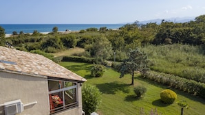 Une maison avec vue sur la mer, un jardin agrémenté d’un banc et une pelouse bien entretenue.