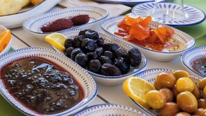 A table with various dishes including olives, lemons, and a bowl of jam. - Elvin Bozcaada (Bozcaada)