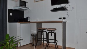 Eine kleine Küche mit einer Mikrowelle, einem an der Wand befestigten Fernseher und zwei Barhocker.