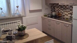 Una cocina compacta con comedor, que presenta armarios de madera clara, salpicadero de azulejos y una lámpara colgante.
