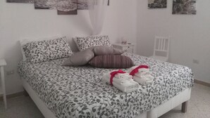 Una cama bien hecha con ropa de cama estampada, una mesita de noche con lámpara y cuadros en las paredes.