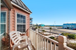 A beachfront property with a balcony, a view of the beach, and a road with a pier in the distance. - Pelican Point 2 Bedroom Townhouse by RedAwning (Navarre)