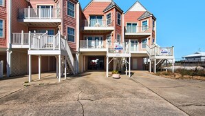 Une propriété située en bord de mer, dotée de plusieurs balcons, d’une entrée couverte et offrant une vue dégagée sur l’océan.