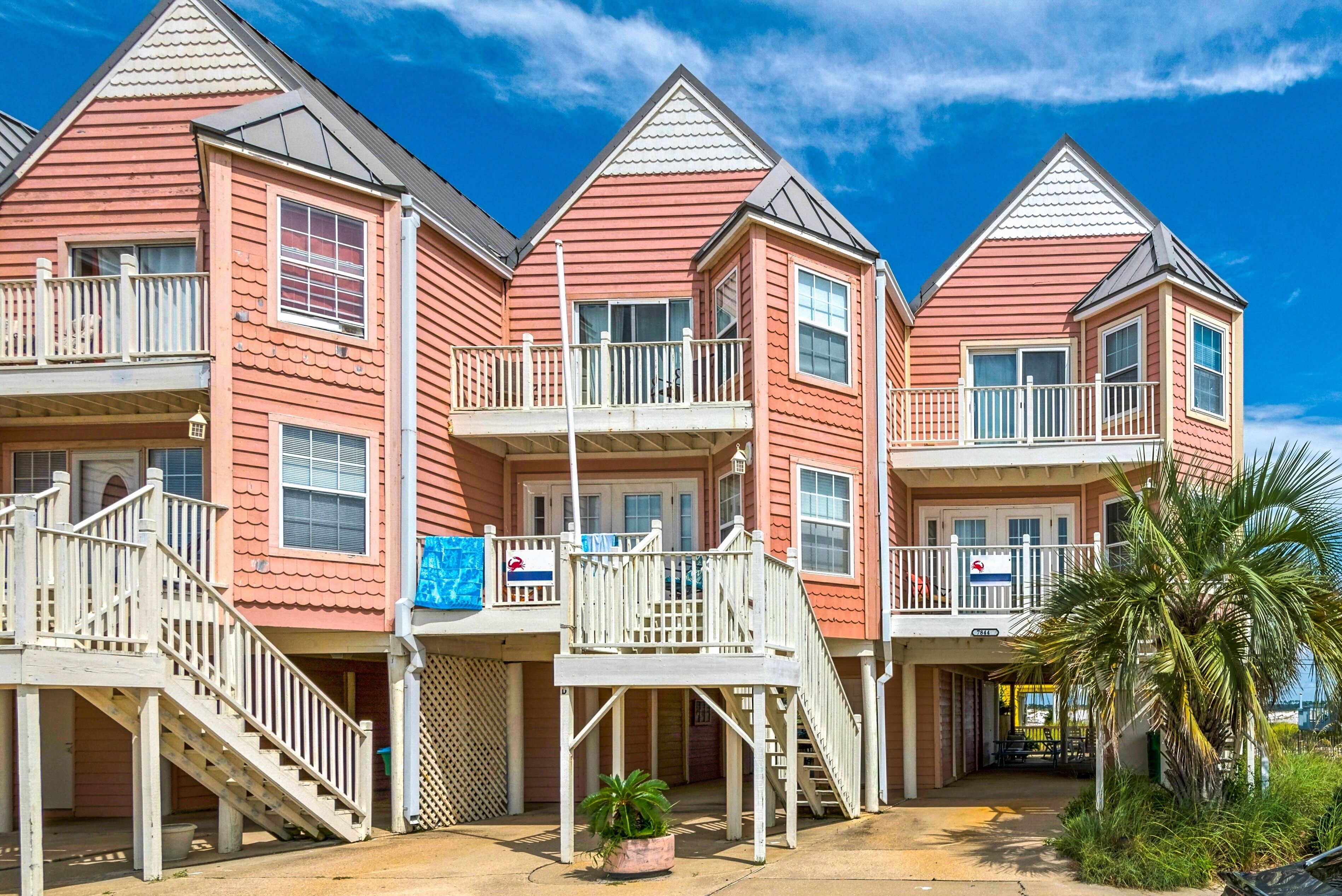 A row of three-story buildings with balconies, a central staircase, and a small outdoor seating area.