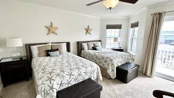 A hotel room with two beds, starfish wall decor, a ceiling fan, and a view of the outside.