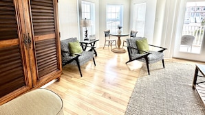 Un salon spacieux avec un meuble en bois, une table à manger avec des chaises et une grande fenêtre qui laisse entrer la lumière naturelle.
