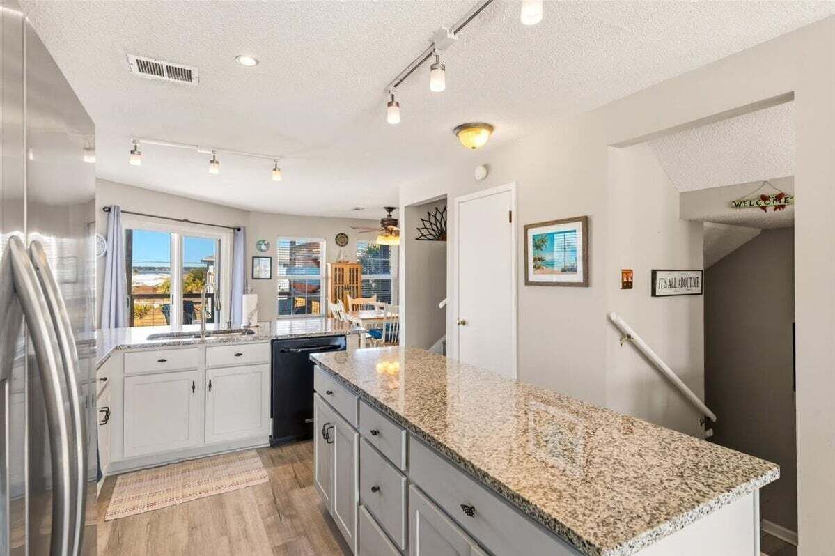 Una cocina moderna con encimeras de granito, armarios blancos y vistas al exterior.