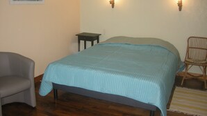 A bedroom with a bed, a chair, a small table, and two wall-mounted lights.