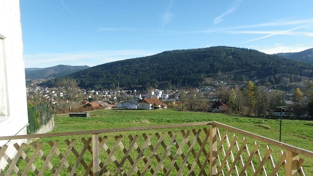 Ein Balkon mit Holzbalkonverkleidung, der auf eine Stadt und ein Gebirge blickt.