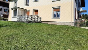 Ein zweistöckiges Gebäude mit Balkon, einer kleinen Veranda und einem Blumengarten.