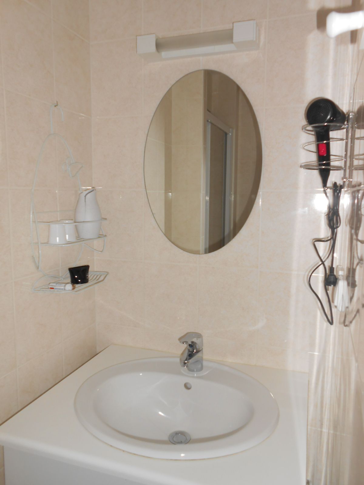 Une salle de bain équipée d’un lavabo, d’un miroir et d’un sèche-cheveux.