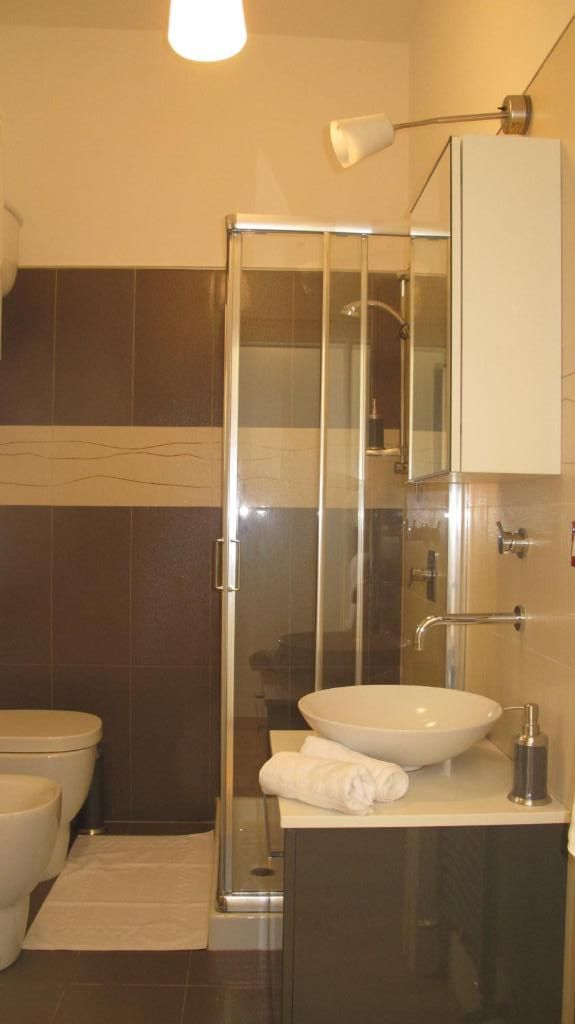 Un baño con ducha de vidrio, lavamanos blanco y un inodoro.