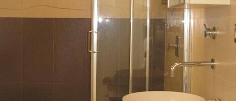 Un baño con ducha de vidrio, lavamanos blanco y un inodoro.