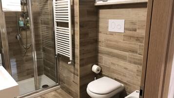 Un baño moderno con cabina de ducha de vidrio, inodoro y bidé.