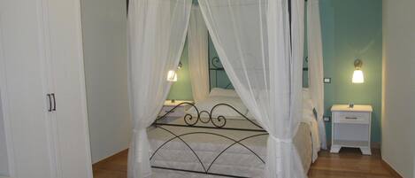 A four-poster bed with a canopy, a bedside table with a lamp, and a wardrobe.