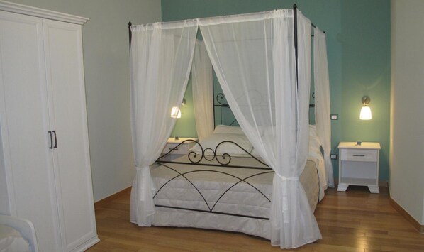 A four-poster bed with a canopy, a bedside table with a lamp, and a wardrobe. - B&B Arco dolce Arco (Benevento)