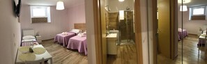 Habitación con dos camas, ducha y una mesita con toallas.