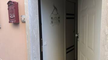 Ein Flur mit einer Tür, auf der “BENVENUE” steht, und einem Briefkasten an der Wand.