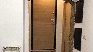 A hallway with a wooden door, a radiator, and a stone accent wall. - B&B Arco dolce Arco (Benevento)