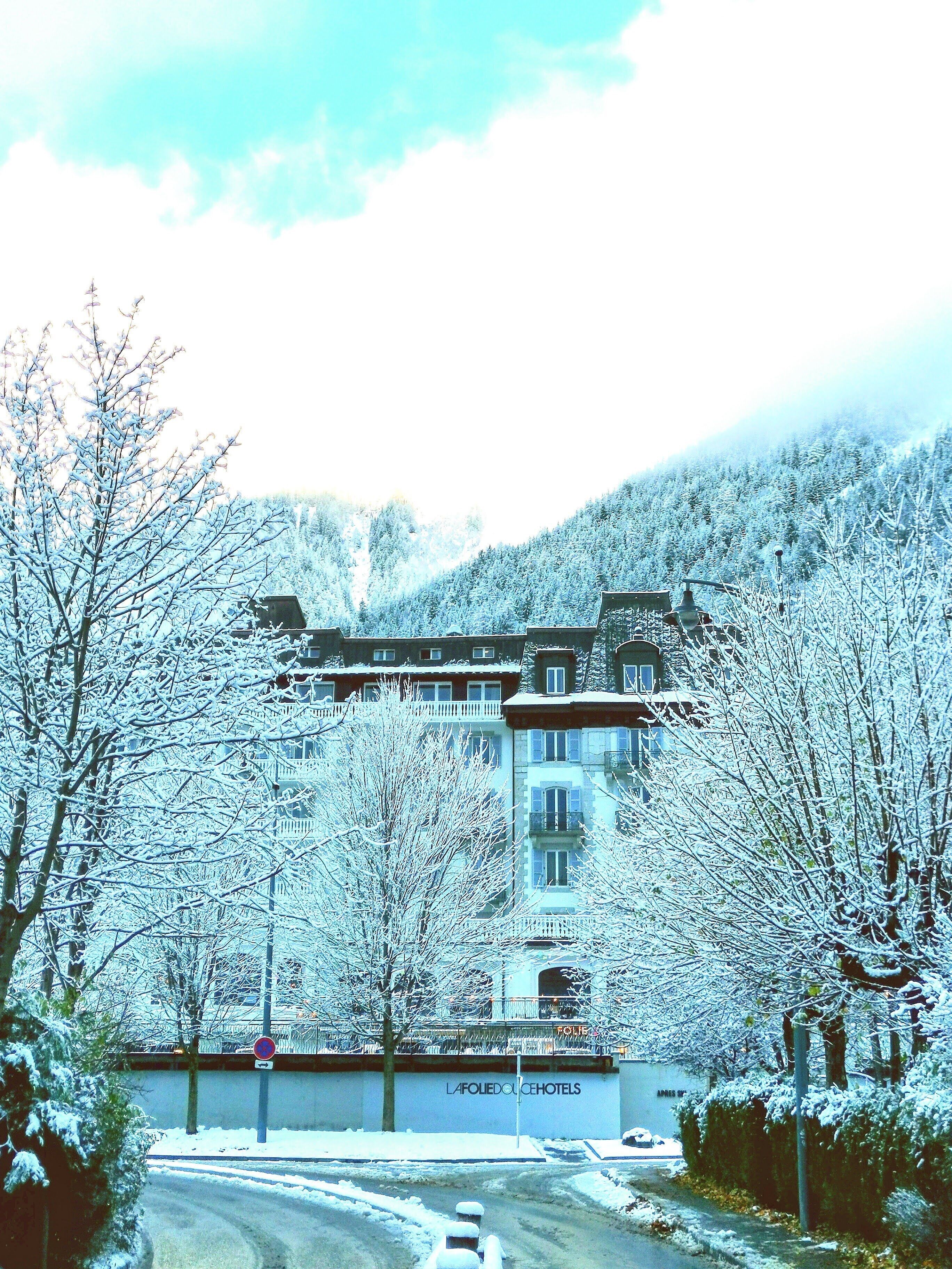 A hotel with a snow-covered landscape, a road, and a sign for "La Folie Dolce Hotels".