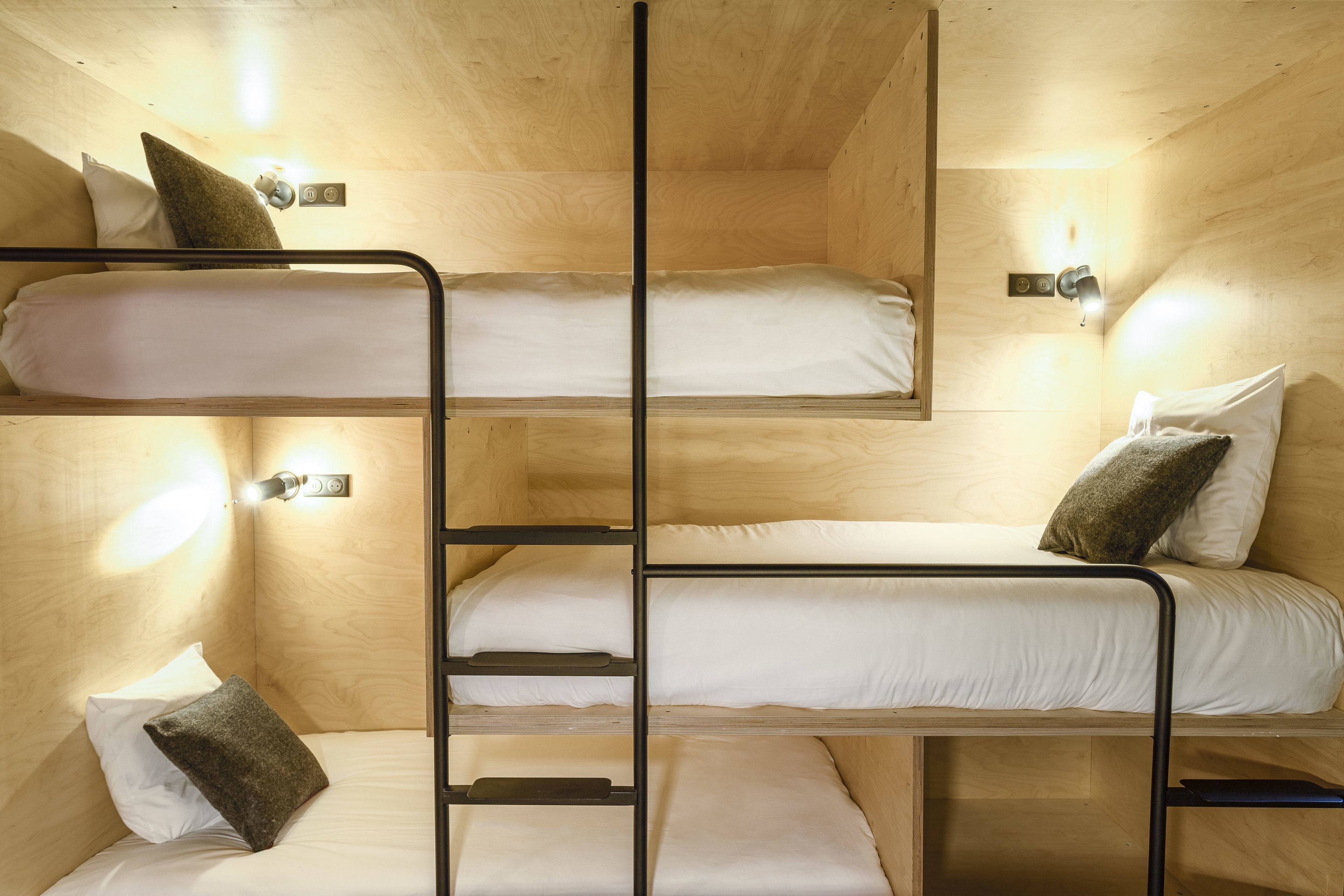 A bunk bed room with wooden walls and built-in lighting.