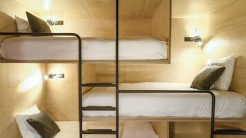 A bunk bed room with wooden walls and built-in lighting.