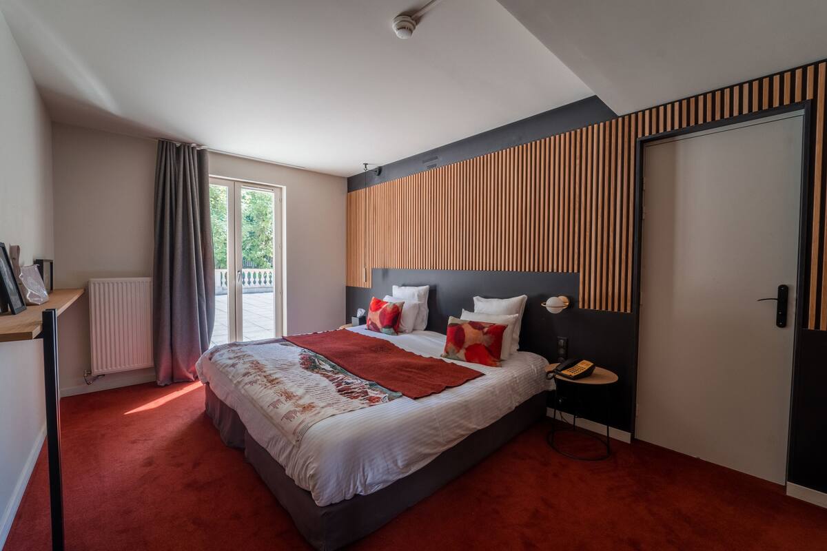 Une chambre moderne avec un grand lit, une table de chevet, un radiateur et une fenêtre avec des rideaux.