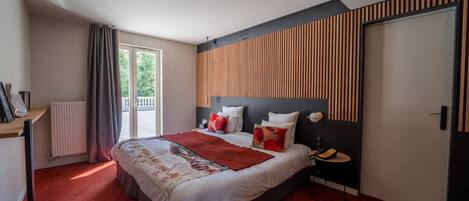 A modern bedroom with a large bed, a bedside table, a radiator, and a window with curtains.