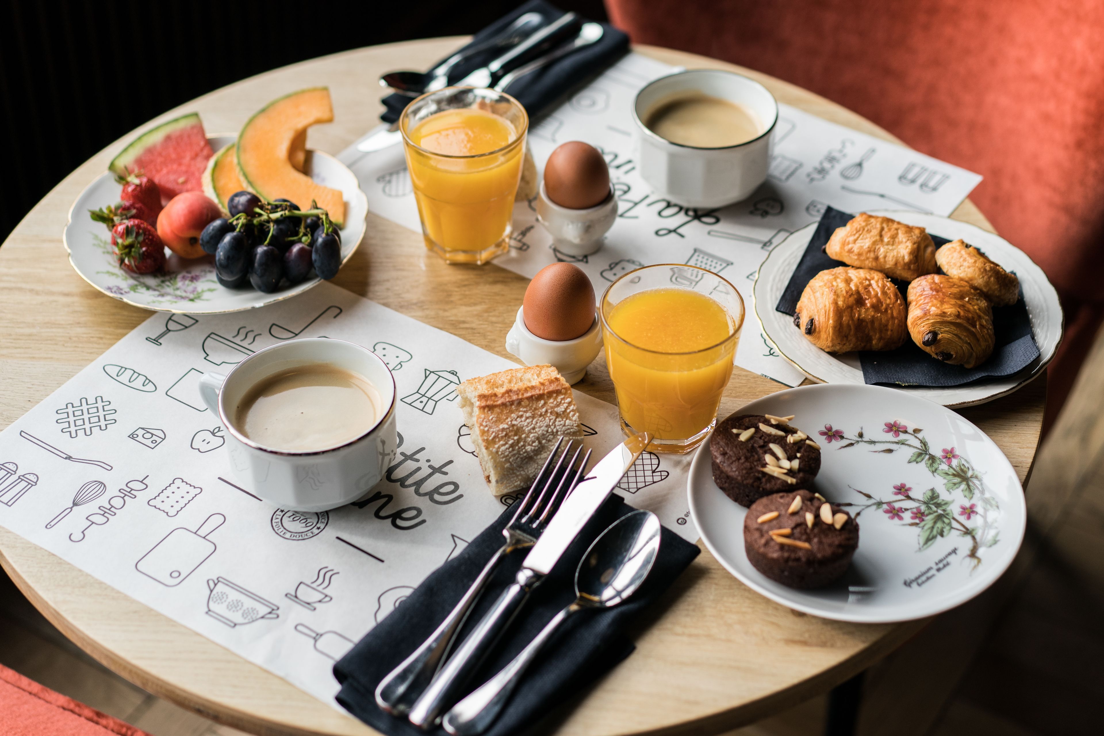 A breakfast table with various food items, including fruits, pastries, and beverages.