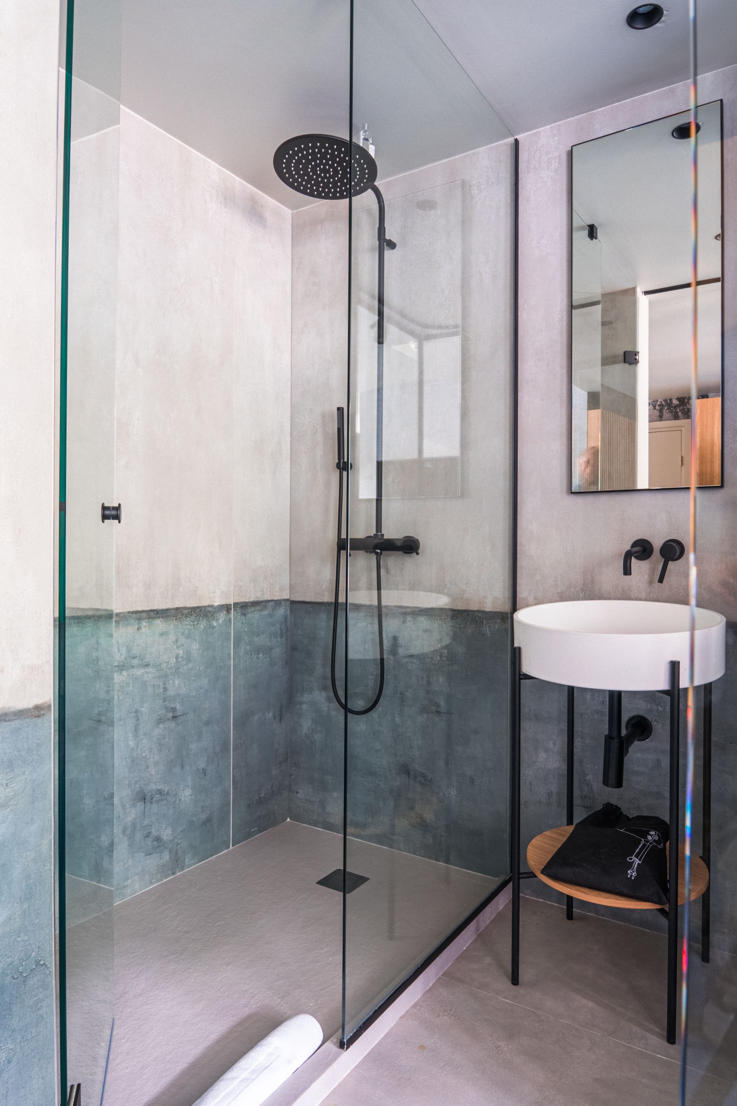 A modern bathroom with a glass-enclosed shower, a white sink, and a mirror.