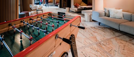 A room with a foosball table, a sofa, and a patterned rug.