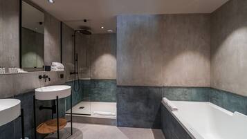 Un baño moderno con un espejo grande, dos lavamanos, una bañera y una zona de ducha.