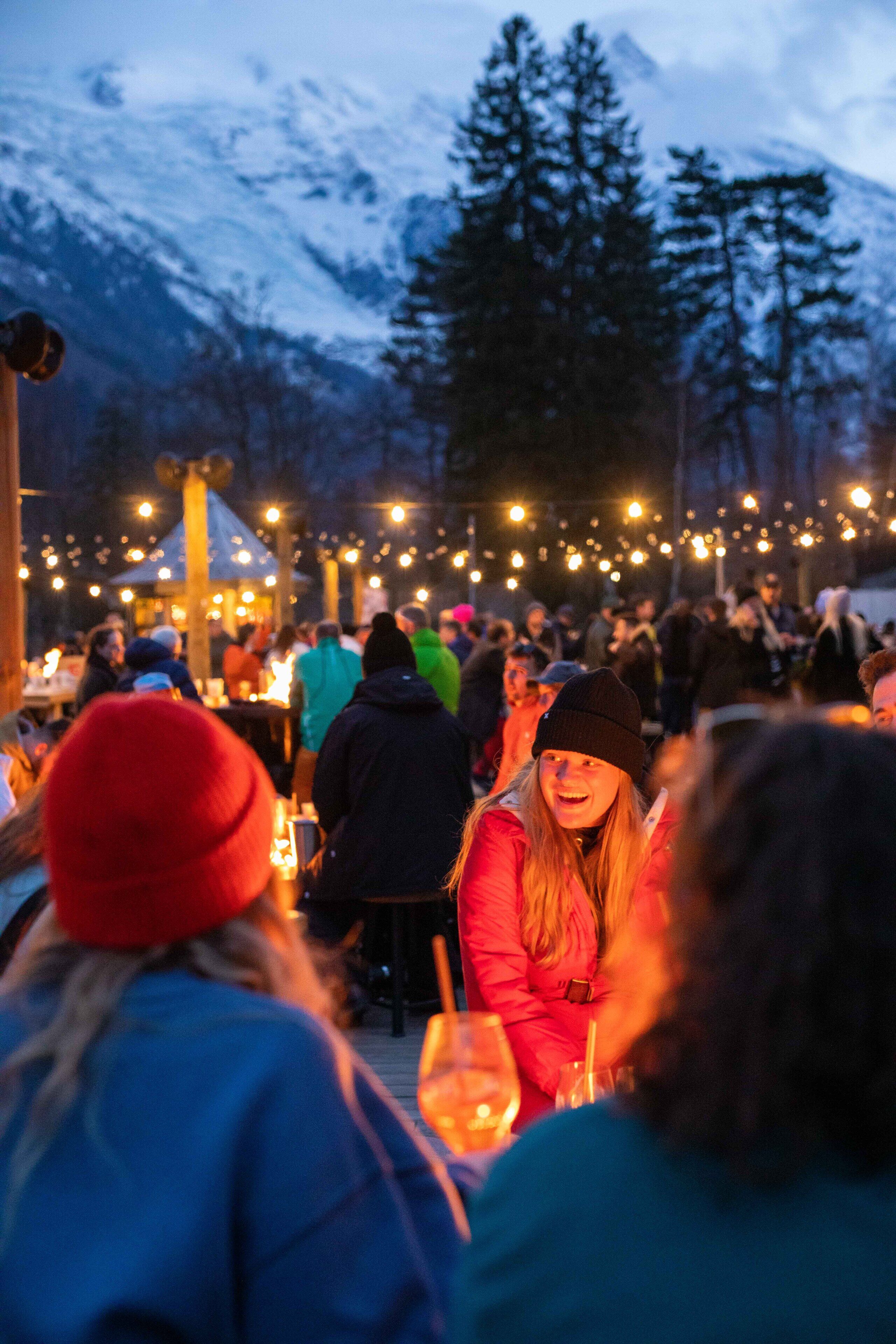 A group of people gathered outdoors at night, with a mountainous backdrop.