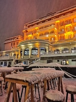 Un hotel con un patio central, mesas cubiertas de nieve y una fachada iluminada.