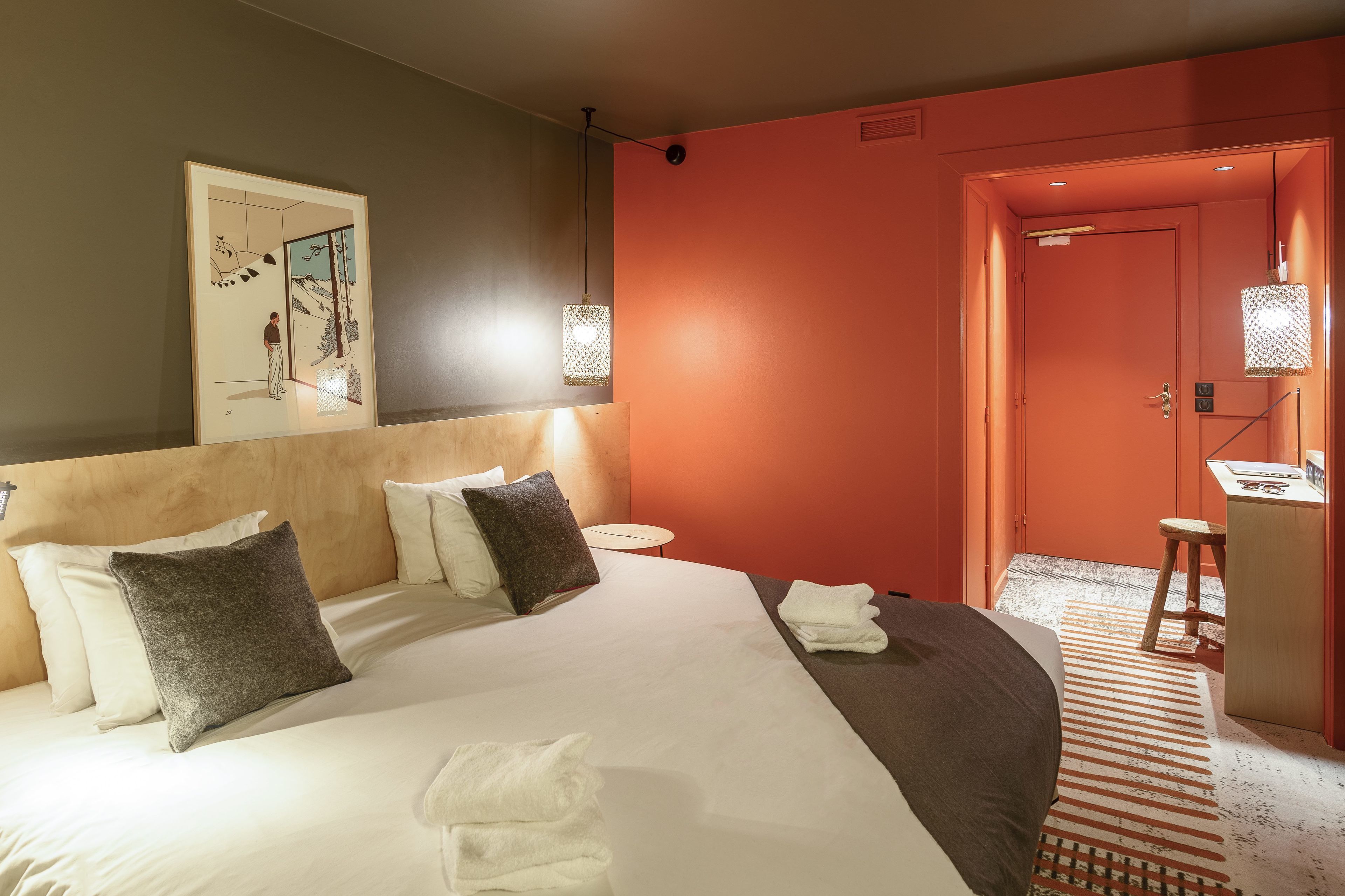 Une chambre d’hôtel avec un grand lit, une table de chevet, un miroir et une porte donnant sur une salle de bain.