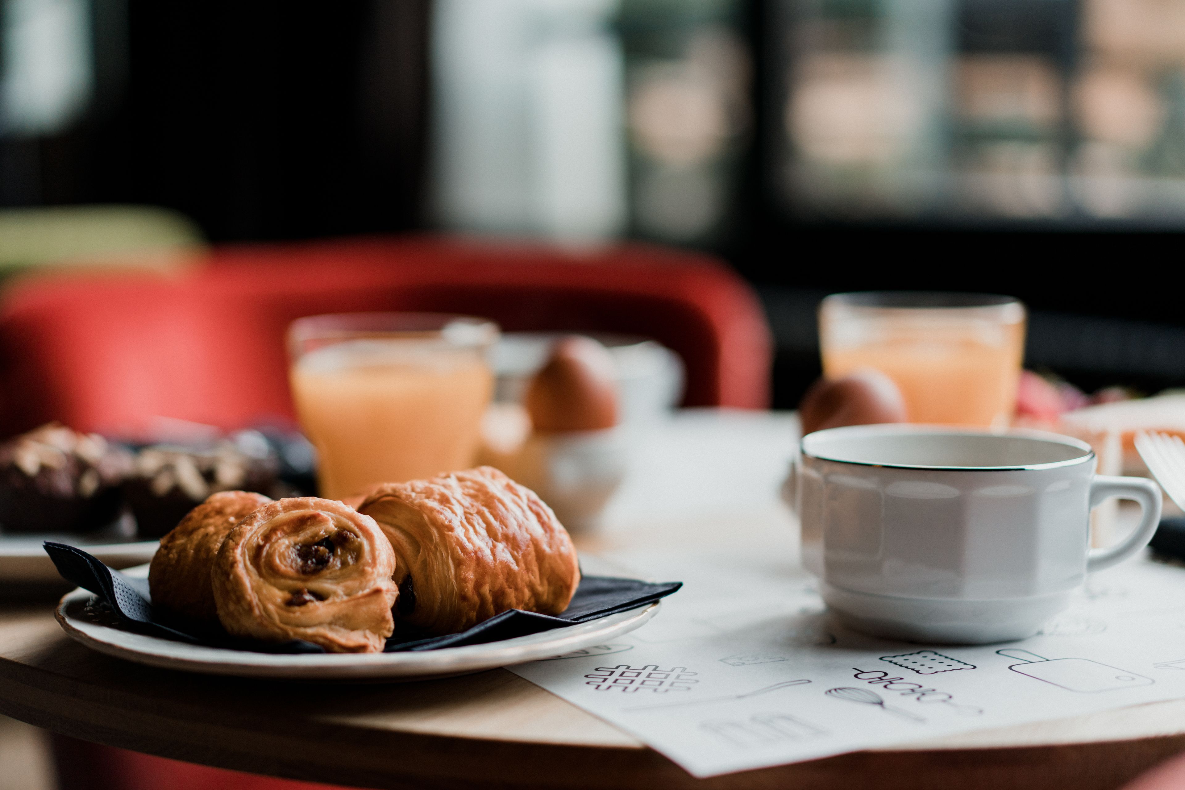 A breakfast setting with croissants, a cup of coffee, and a glass of orange juice on a table.