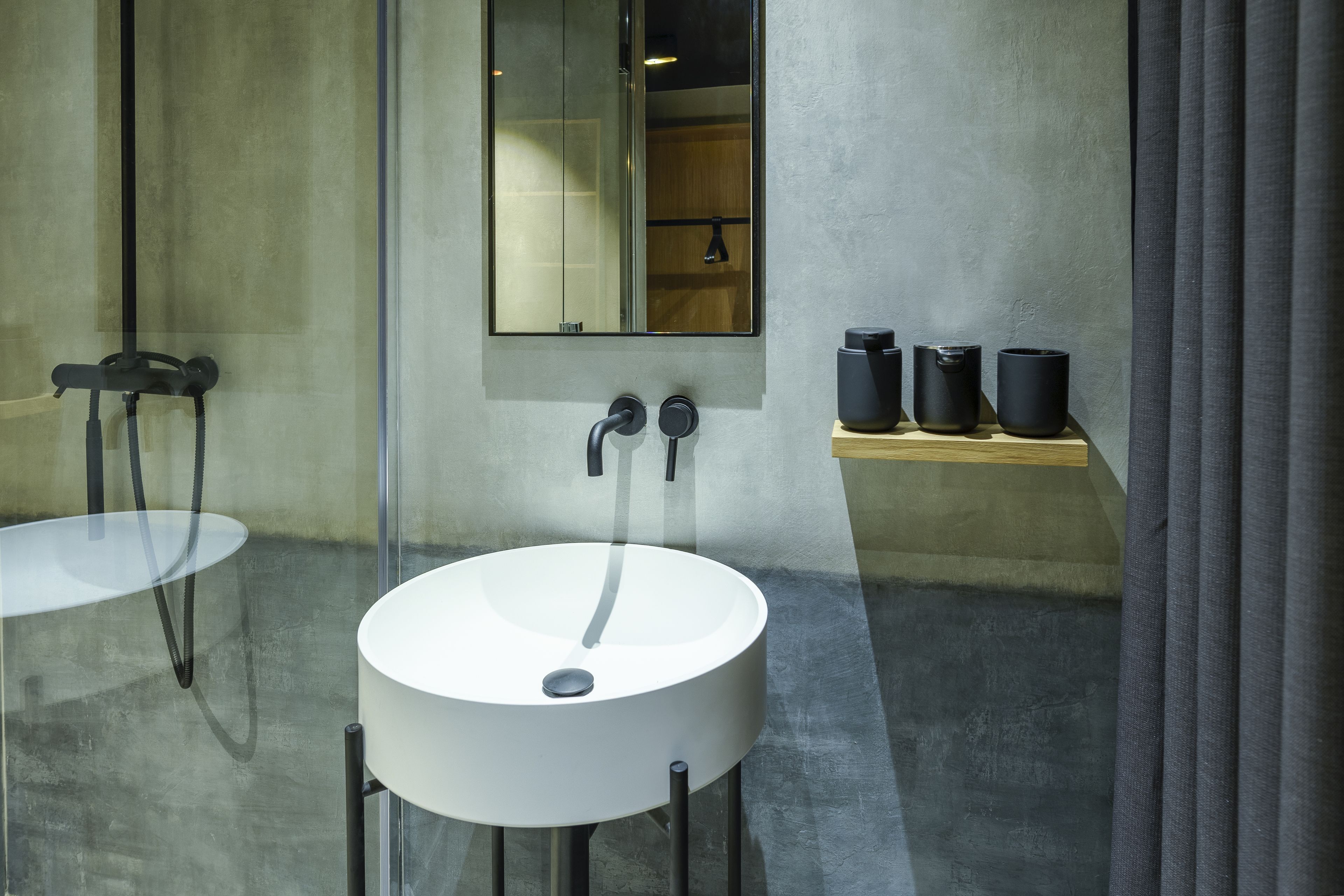 A modern bathroom with a large mirror, two sinks, and a shelf with black containers.