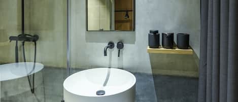 Un baño moderno con un espejo grande, dos lavamanos y un estante con recipientes negros.