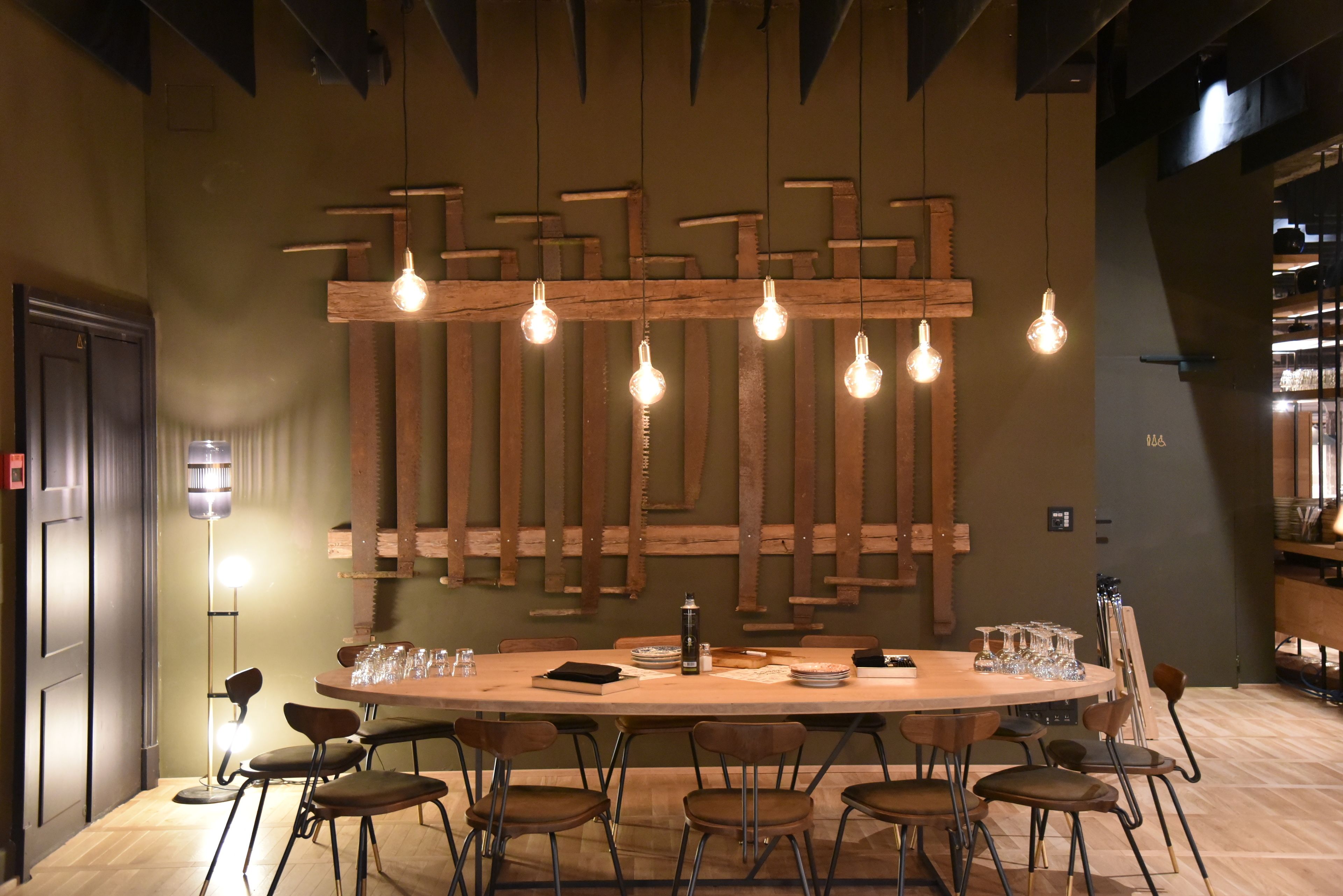 A modern dining area with a wooden table set for six, surrounded by chairs.