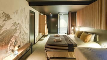 A modern hotel room with a large bed, a bedside table, and a wall-mounted shelf.