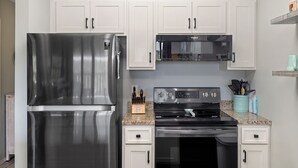 Una cucina moderna con elettrodomestici in acciaio inossidabile, mobili bianchi e piani di lavoro in granito.
