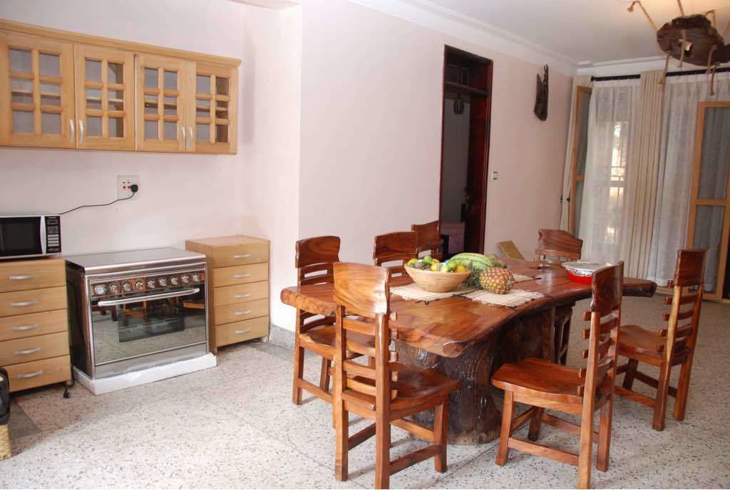 Una cocina con armarios de madera, un horno de acero inoxidable y una mesa de comedor con sillas de madera.