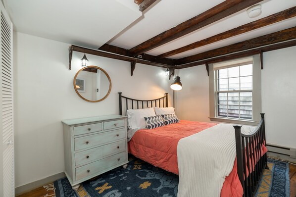 A bedroom with a bed, a dresser, a window, and a mirror.