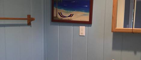 Un baño con inodoro, lavamanos y un cuadro enmarco con una playa.
