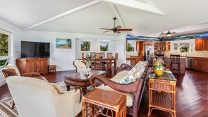 Un amplio salón con una televisión grande, muebles de madera y una mesa de comedor.