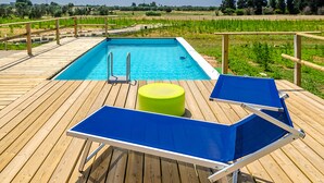 A wooden deck with a pool, two blue sun loungers, and a green stool. - Tenuta Libò (Alezio)